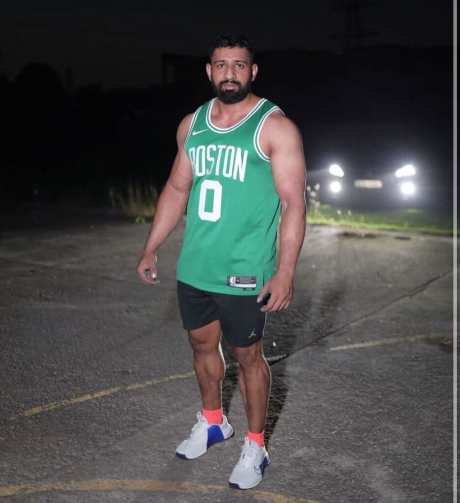 Rajat Dalal posing in a gym, showcasing his fitness and strength as a powerlifter and influencer.

